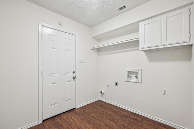 laundry room with cabinets, a textured ceiling, dark hardwood / wood-style flooring, hookup for a washing machine, and hookup for an electric dryer