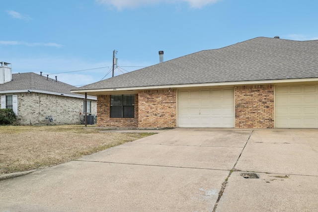 ranch-style home with a garage and central air condition unit