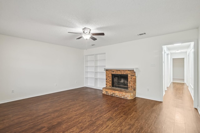 unfurnished living room featuring a textured ceiling, dark hardwood / wood-style flooring, built in features, ceiling fan, and a fireplace