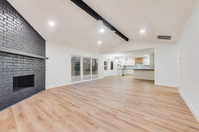 unfurnished living room with lofted ceiling with beams, light wood-type flooring, and a fireplace