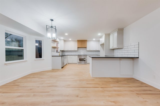 kitchen with pendant lighting, high end stainless steel range oven, backsplash, and white cabinets