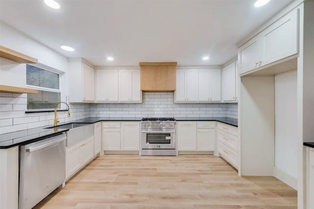 kitchen with stainless steel appliances, sink, white cabinets, and light hardwood / wood-style flooring