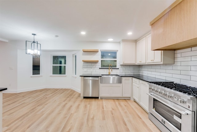 kitchen with appliances with stainless steel finishes, pendant lighting, tasteful backsplash, white cabinetry, and sink