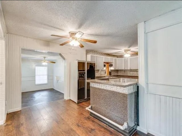 kitchen with decorative backsplash, dark wood finished floors, a peninsula, light countertops, and white cabinetry