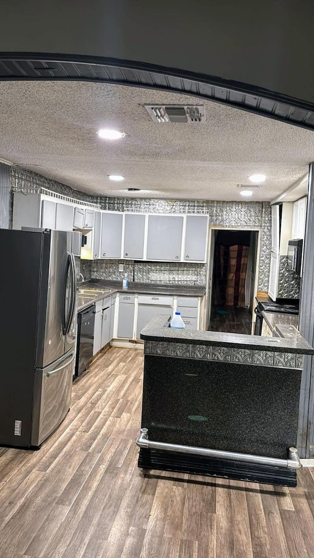 kitchen featuring black dishwasher, light wood finished floors, visible vents, freestanding refrigerator, and white cabinetry