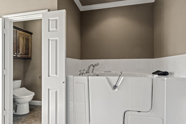 bathroom featuring crown molding, toilet, and a bathing tub