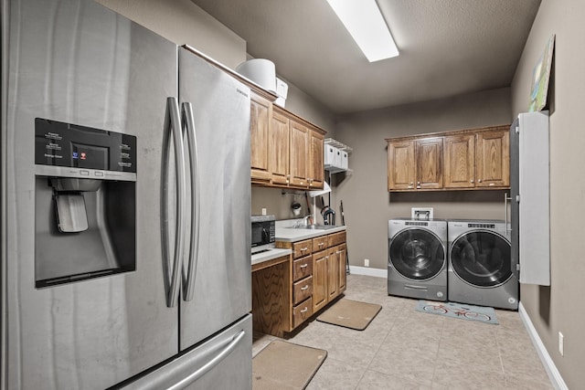 washroom featuring light tile patterned flooring, washing machine and clothes dryer, and sink