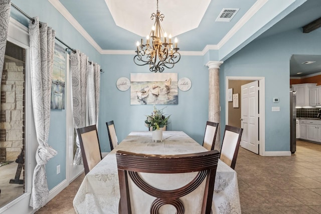 tiled dining area with a tray ceiling, crown molding, an inviting chandelier, and ornate columns