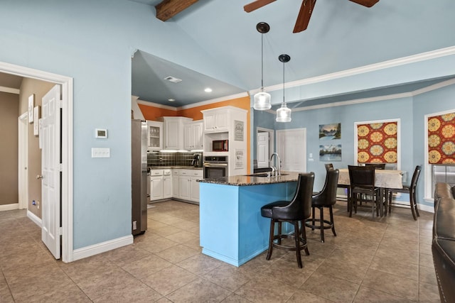 kitchen featuring sink, a breakfast bar area, dark stone countertops, pendant lighting, and white cabinets