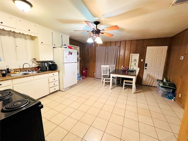 kitchen featuring sink, white cabinetry, black range with electric stovetop, wooden walls, and white fridge