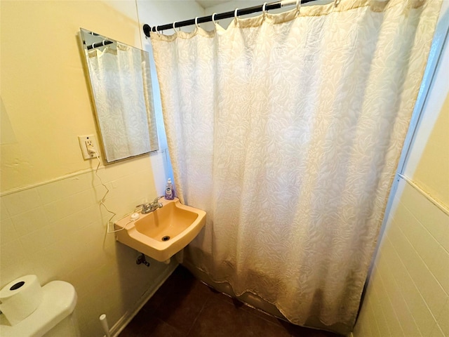 bathroom with tile walls, sink, and toilet