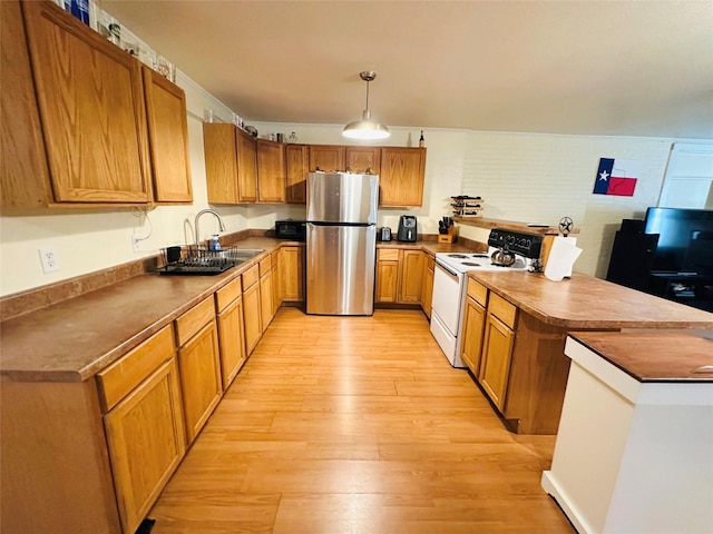 kitchen featuring white electric range oven, sink, hanging light fixtures, light wood-type flooring, and stainless steel refrigerator