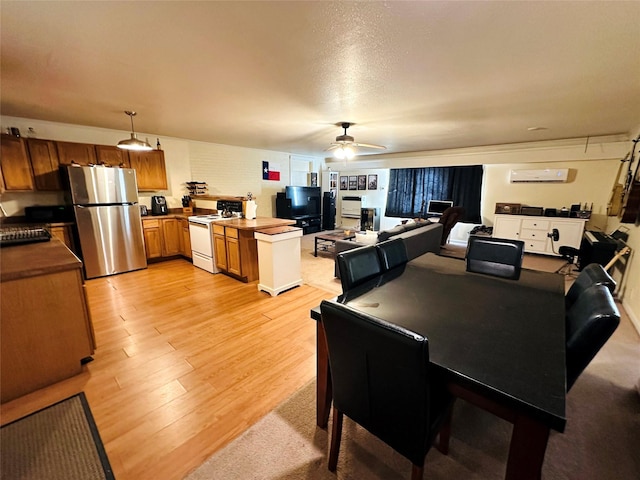 dining room with a textured ceiling, a wall mounted AC, ceiling fan, and light wood-type flooring