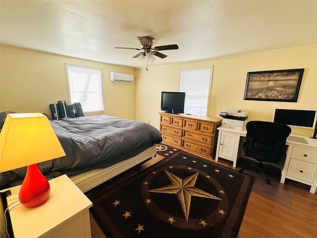 bedroom with ceiling fan, dark hardwood / wood-style floors, a wall unit AC, and a textured ceiling