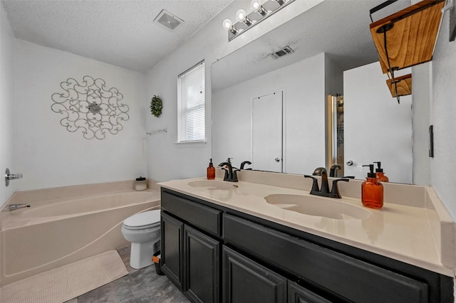 bathroom with a tub to relax in, toilet, a textured ceiling, and vanity