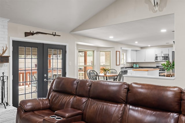 living room featuring vaulted ceiling, sink, and french doors