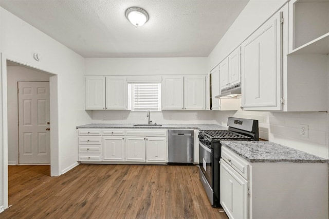 kitchen with appliances with stainless steel finishes, dark hardwood / wood-style floors, white cabinetry, sink, and light stone counters