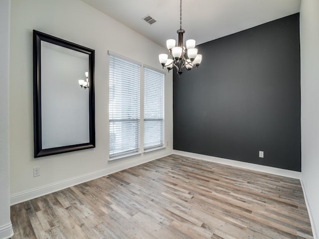 unfurnished room with a chandelier and light hardwood / wood-style flooring