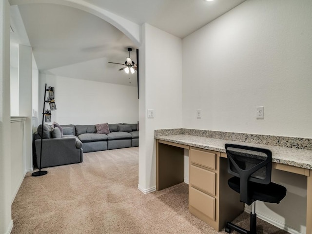 home office featuring light carpet, built in desk, lofted ceiling, and ceiling fan