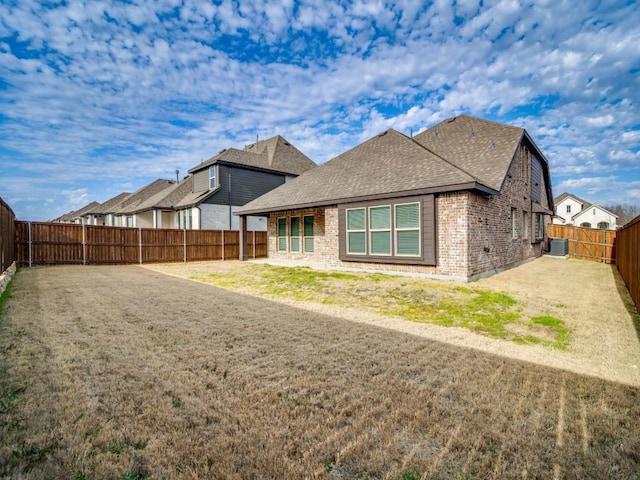 back of house with central AC and a lawn