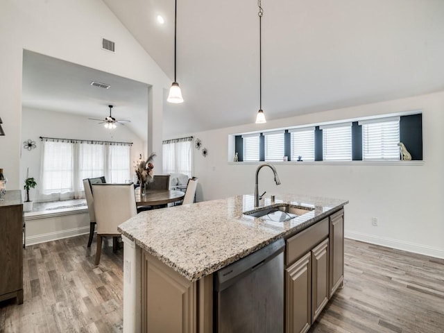 kitchen featuring pendant lighting, dishwasher, lofted ceiling, sink, and a center island with sink