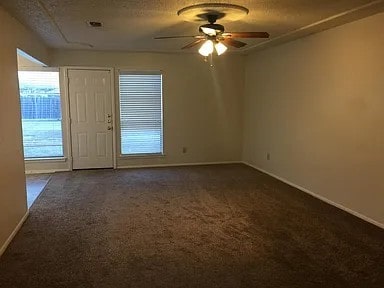 unfurnished room featuring ceiling fan, dark carpet, and a textured ceiling