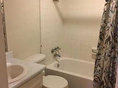 full bathroom with vanity, shower / bath combination with curtain, and toilet