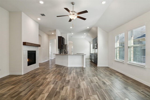 unfurnished living room featuring dark wood-type flooring, a tile fireplace, and ceiling fan