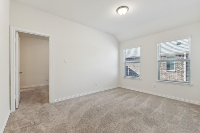 carpeted empty room featuring lofted ceiling