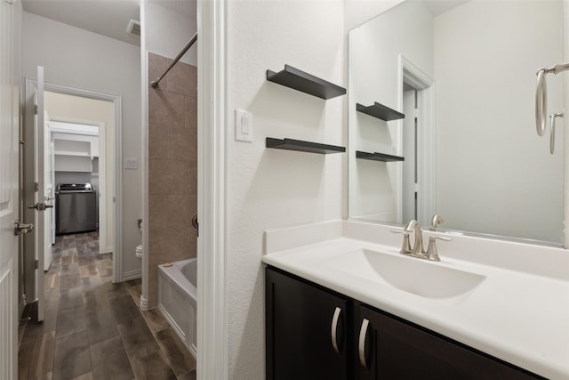 bathroom with vanity, tiled shower / bath combo, and washer / dryer