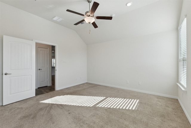 carpeted spare room featuring vaulted ceiling, ceiling fan, and plenty of natural light