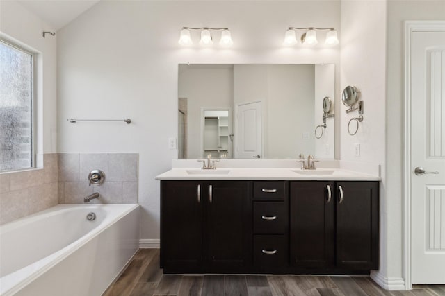 bathroom with vaulted ceiling, vanity, and a bathtub