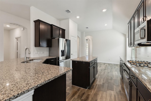 kitchen with sink, light stone counters, dark hardwood / wood-style floors, a kitchen island, and stainless steel appliances