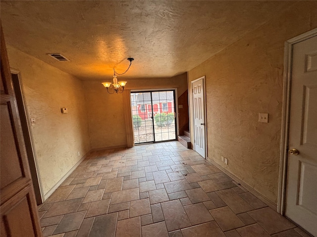 unfurnished room featuring a textured ceiling and a notable chandelier