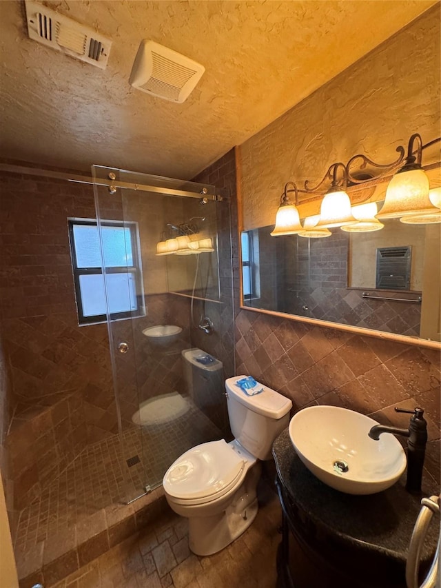 bathroom featuring tile walls, vanity, a shower with shower door, and toilet