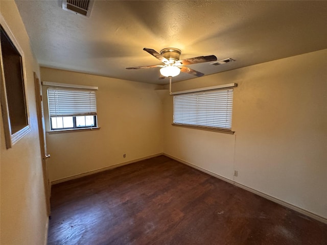 empty room featuring dark wood-type flooring, a textured ceiling, and ceiling fan