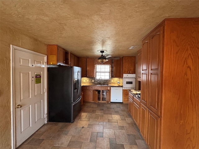 kitchen with white appliances, sink, decorative backsplash, and a textured ceiling