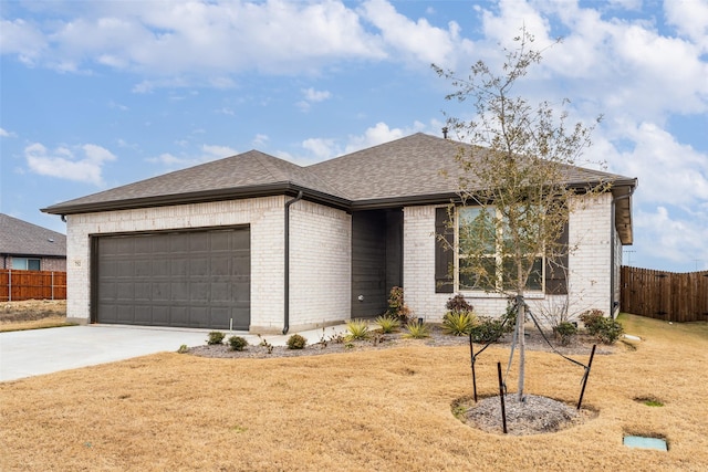 view of front facade featuring brick siding, fence, roof with shingles, driveway, and an attached garage