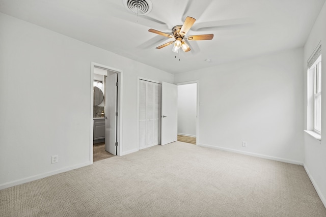 unfurnished bedroom featuring light colored carpet, ceiling fan, and ensuite bathroom