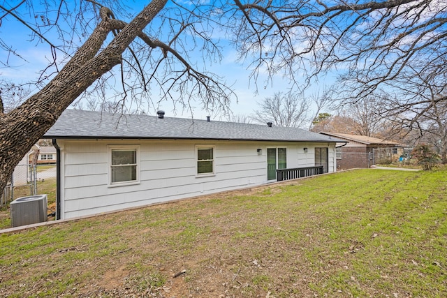 back of property featuring central AC unit and a lawn