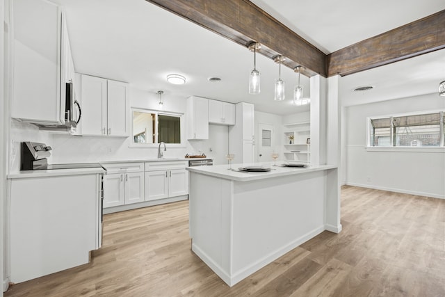 kitchen featuring sink, tasteful backsplash, hanging light fixtures, light hardwood / wood-style floors, and white cabinets