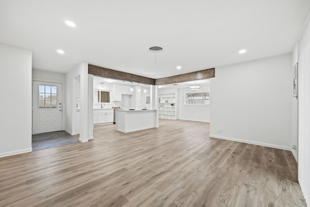 unfurnished living room with sink and light hardwood / wood-style floors