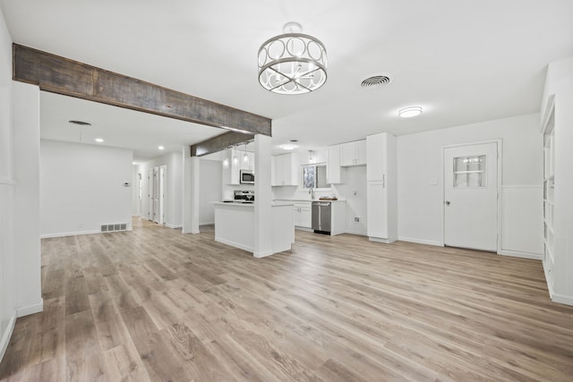 unfurnished living room with sink, a notable chandelier, and light hardwood / wood-style floors