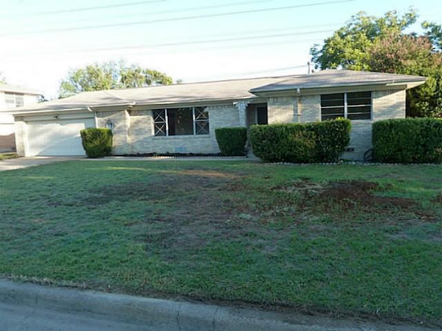 ranch-style home featuring a garage and a front yard