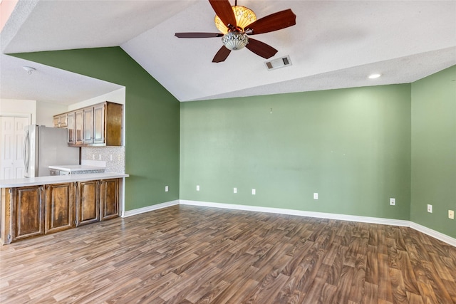 kitchen with lofted ceiling, stainless steel fridge, ceiling fan, tasteful backsplash, and light wood-type flooring