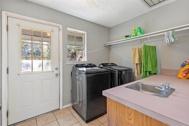 laundry room featuring sink, washing machine and dryer, a textured ceiling, and light tile patterned floors