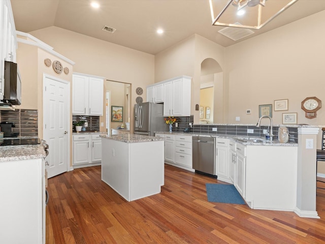 kitchen featuring tasteful backsplash, stainless steel appliances, a center island, and white cabinets