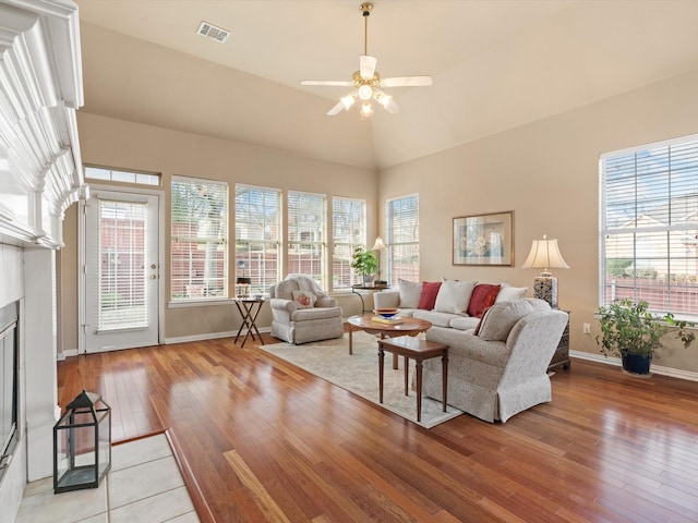 living room with ceiling fan, vaulted ceiling, and light wood-type flooring