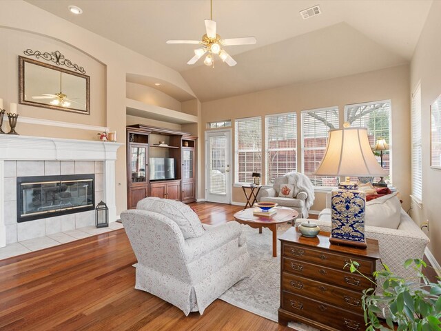 living room with a tile fireplace, plenty of natural light, ceiling fan, and light hardwood / wood-style floors