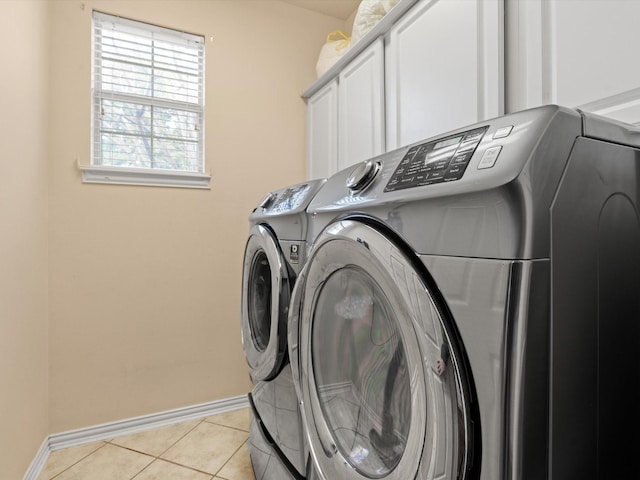 laundry room with cabinets, light tile patterned floors, and washer and clothes dryer